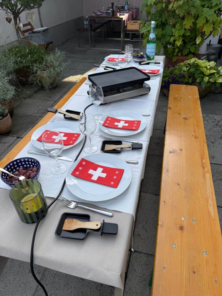 Megterített asztal raclette-sütővel és svájci zászlós szalvétákkal
